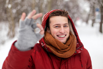 happy man in winter jacket showing ok hand sign