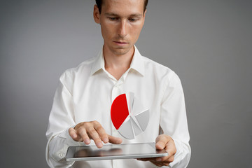 Man in white shirt working with pie chart on a tablet computer, application for budget planning or...