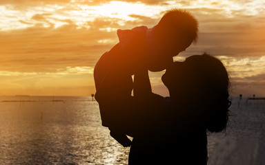 Silhouette of mother and baby on sunset
