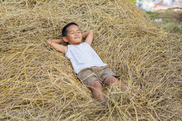 Happy Children wearing a white shirt sleeping on straw.