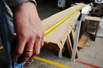 carpenter measures the wooden beam