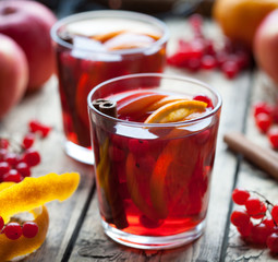 Sangria in glasses with ingredients - orange and apple slices, berries, cinnamon sticks in a wooden table. Square format. Creative decoration.
