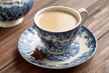 Masala tea chai latte homemade traditional Indian milk with spices beverage in porcelain cup on wooden table background