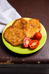 Potato pancakes with meat and tomatoes on green plate in Belarus