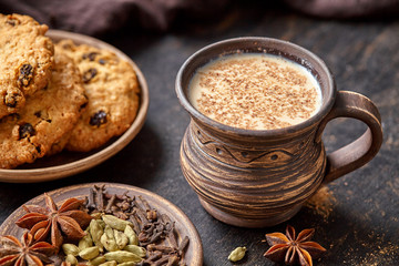 Masala pulled tea chai latte traditional hot Indian sweet milk spiced drink, ginger, fresh spices and herbs blend, anise organic infusion healthy wellness beverage teatime ceremony in rustic clay cup