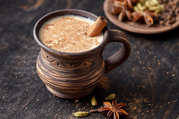 Masala pulled tea chai latte homemade hot Indian sweet milk spiced drink, ginger, fresh spices and herbs blend, anise organic infusion healthy wellness beverage teatime ceremony in rustic clay cup - obrazy, fototapety, plakaty