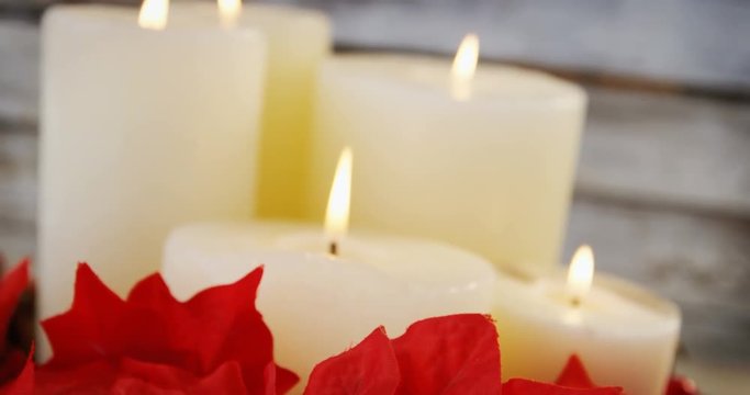 Candles decorated with flowers on wooden plank