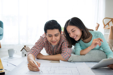 Attractive young asian adult couple looking at house plans.
