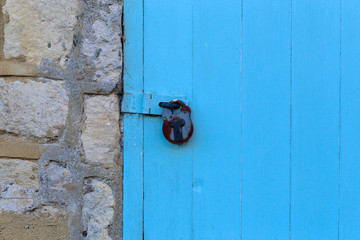 Blue door on stone wall locked with vintage locker
