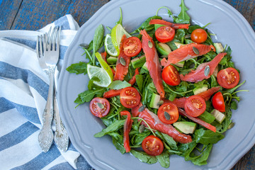 Salted salmon with herbs, tomatoes and salad on a wooden board. Love for a healthy raw food concept
