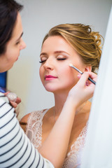 Wedding preparation. Professional makeup artist applies makeup bride