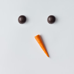 Snowman face made of cookies and carrot. Minimal holiday concept