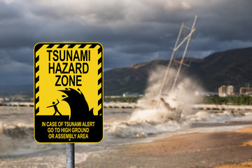 Sign warning of a tsunami. In the background a ship and a storm in the Bay. Sunset.