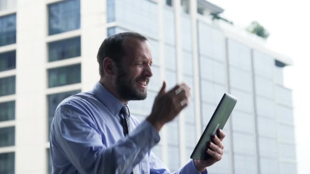 Unsuccessful businessman with tablet getting bad news standing on terrace
