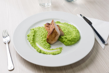 Detail of grilled chicken steak with mashed green peas up on a plate