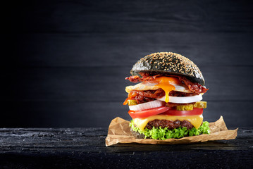 Black burger with egg and bacon on the wooden table - 127803998