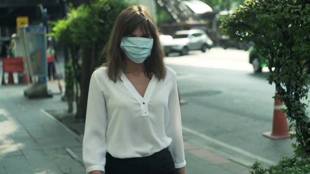 Young woman with mask walking near street in city 
