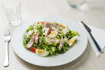 Nutritious vegetable salad with boiled egg slices and salmon
