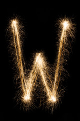 English Letter W from sparklers alphabet on black background.