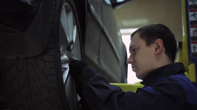 Low section of male mechanic repairing car's tire in repair shop