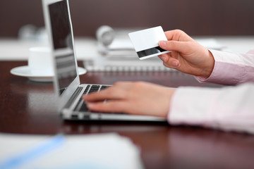 Close up of business woman hands using credit card and laptop computer