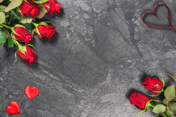 Red roses, hearts and ribbon on black marble board. Valentines Day background