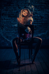 Plakat The bad girl with a bottle of whiskey sitting on a chair, and smoking. The room is dark and scary.