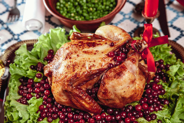 Roasted chicken, table setting. Thanksgiving table served with baked turkey, decorated with lettuce and pomegranate seeds. Christmas dinner by candlelight