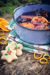 Mulled wine with spices and ingredients on wooden background