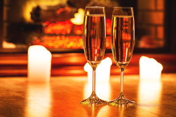 Beautiful two glasses of champagne standing on the table in the background of a blurred room with a decorated Christmas tree and candles. Soft focus. Shallow DOF