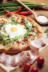 Fresh pizza with ingredients on wooden table