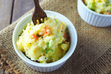 Close up of a bowl of potato salad on a wooden table.
