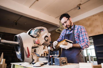 Young craftsman in uniform working at carpentry