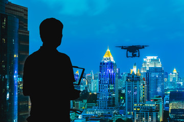 Silhouette of Man using drone to monitor the city at night.