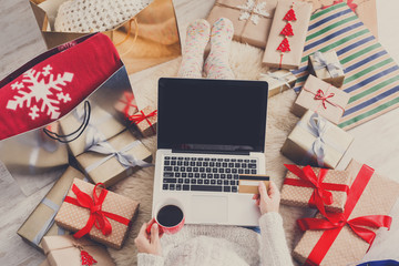 Fototapeta premium Woman makes christmas shopping online with laptop, above view