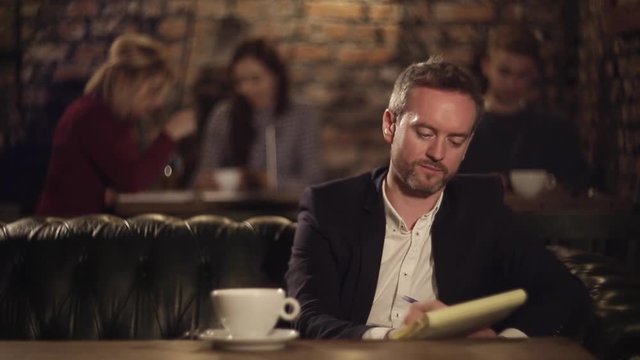 Man texting on notebook and drinking tea in cafe