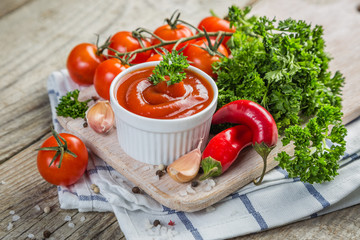 Ketchup and ingredients on wood background
