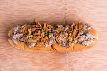 Hotdog topped with caramelized onions, beef and cheddar sauce
