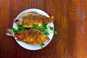 fried fish on a white plate on a wooden background
