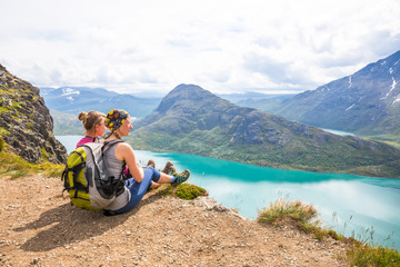 Young woman hiking on Besseggen. Happy girl enjoy beautiful lake and good weather in Norway.