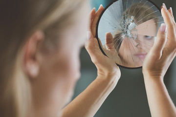 Woman holding small broken mirror