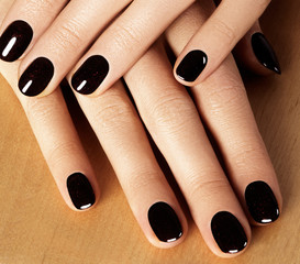 Beautiful female fingers with shiny gel manicure bright pink color. Holding nail polish bottle. Care about female hands, healthy soft skin. Spa & cosmetics