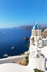 Fototapeta na wymiar Greece. Santorini Island. The bell tower of the Orthodox Church with the traditional blue dome and white plastered walls in the town of Oia