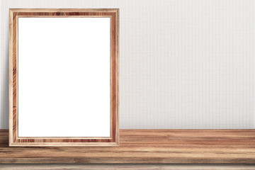 Blank wood picture frame is on top of wood table.