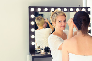 Fototapeta na wymiar make up artist doing professional make up of young woman
