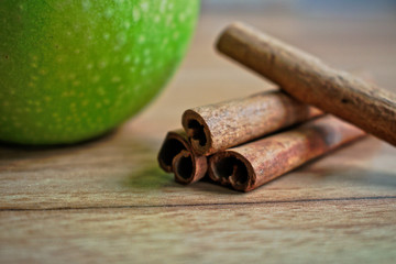 Green apple and cinnamon sticks on a wooden table