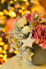 Pot of snowy pink roses and hydrangea as christmas decoration tree on bokeh lights