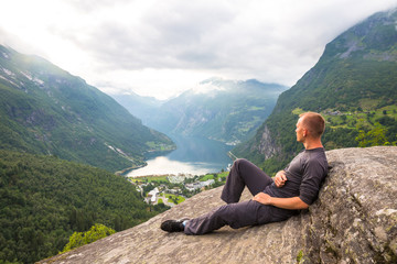 Naklejka na ściany i meble Young men relax on Geiranger fjord. Happy friends enjoy beautiful lake and good weather in Norway.