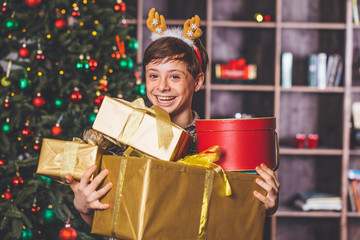 Obraz na płótnie Canvas Christmas concept. New Year. Happy child holding a Christmas present. Boy with Christmas gifts, Christmas tree in the background. Boy and a lot of Christmas gifts