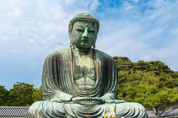 It is the Great Buddha of Kamakura, which is surrounded by the green of the leaves. I photographed the Great Buddha in Japan Kamakura, Kanagawa Prefecture.